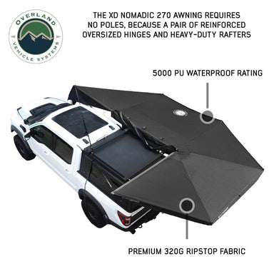 Angled top-down view of a white pickup truck with an OVS Nomadic 270 Awning partially deployed. The black awning extends from the side and rear of the truck, highlighting its poleless design and durable materials, with text annotations pointing to the waterproof rating and ripstop fabric