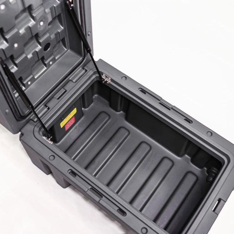 Image of an open dark gray storage box, revealing the spacious interior with a ribbed bottom and supported by gas struts, angled top view on a white background.