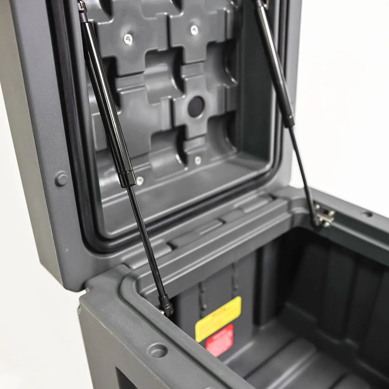 Image of two black gas struts supporting the open lid of a dark gray storage box, revealing the interior, angled top view on a white background.