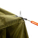 Image of a close-up detail of the 23ZERO Armadillo A2 Plus rooftop tent annex room, showing a guy rope with an orange tensioner attached to a plastic stake on the green fabric. The close-up shot focuses on the detailed attachment point