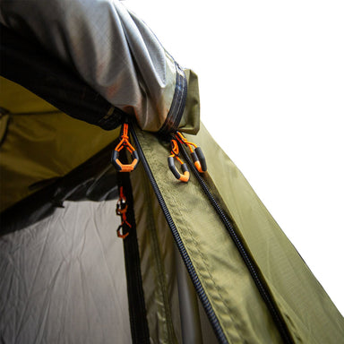 Image of the zippered entrance of the 23Zero Armadillo A3 Plus Annex, a close-up shot of the khaki-colored fabric with its heavy-duty zippers and orange zipper pulls, angled view on a white background