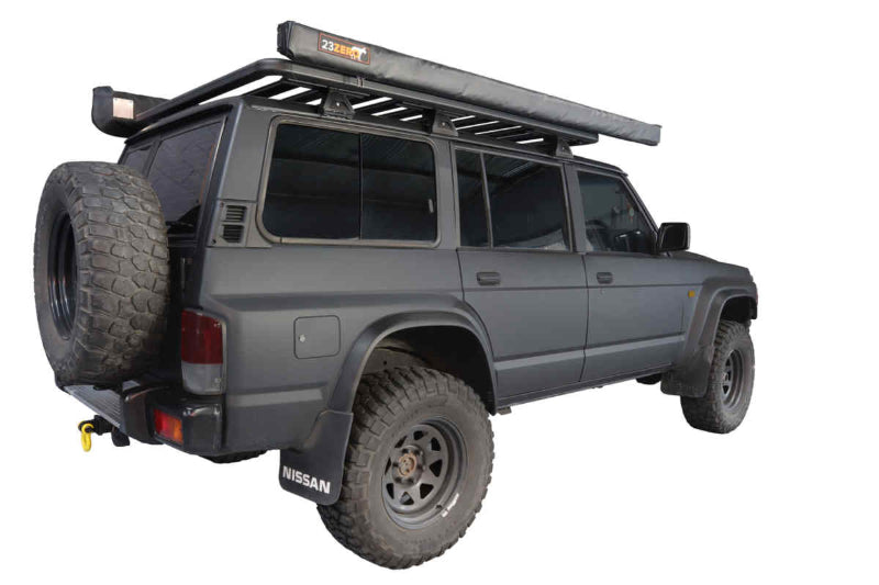 Image of a dark grey Nissan SUV with a black roof rack and a rolled-up Peregrine Awning mounted on top, showing the "23ZERO" logo. A spare tire is attached to the rear of the vehicle, which is presented against a white background
