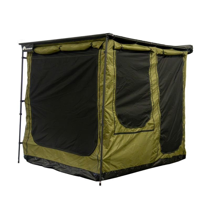 Image of a fully enclosed Bushman awning room, showcasing its green fabric with large black mesh windows on the front and side panels. The awning room is depicted from an angled front and side view on a white background