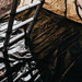 Close-up image looking down at a metallic ladder resting on a black ground tarp inside a tent, with a hint of tan tent fabric visible in the upper right corner.