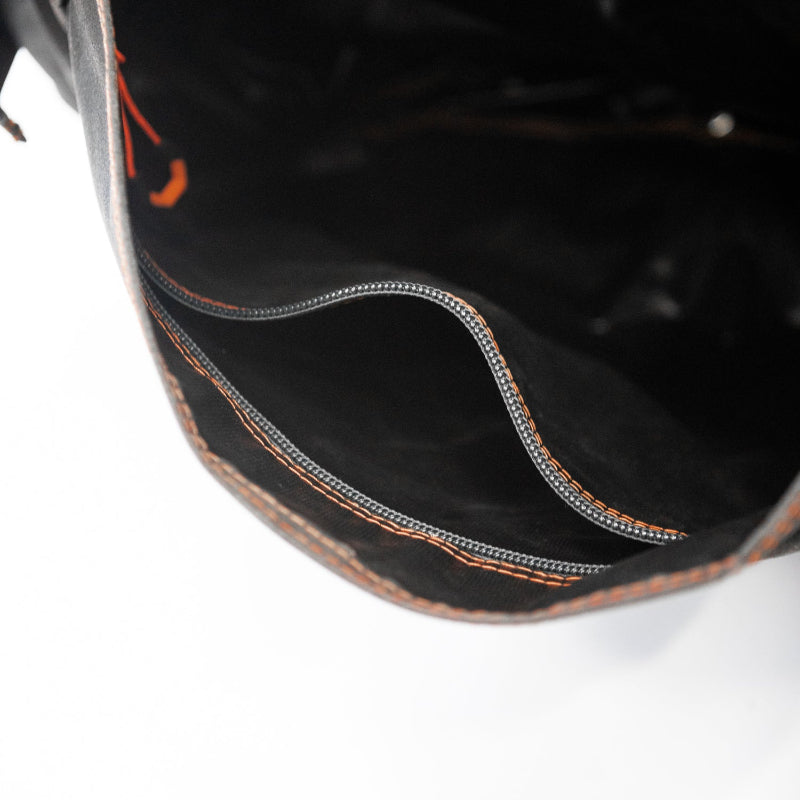 Image showing the interior of a black bag with two open zippered compartments, highlighted by orange stitching on the fabric edges.