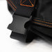 Image of a close-up of a black plastic buckle on a black fabric strap, with orange stitching visible on the surrounding black material.