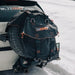 Image of a black 23ZERO spare tire storage bag with orange stitching and straps, mounted on the rear spare tire of a white vehicle, set against a snowy outdoor background.