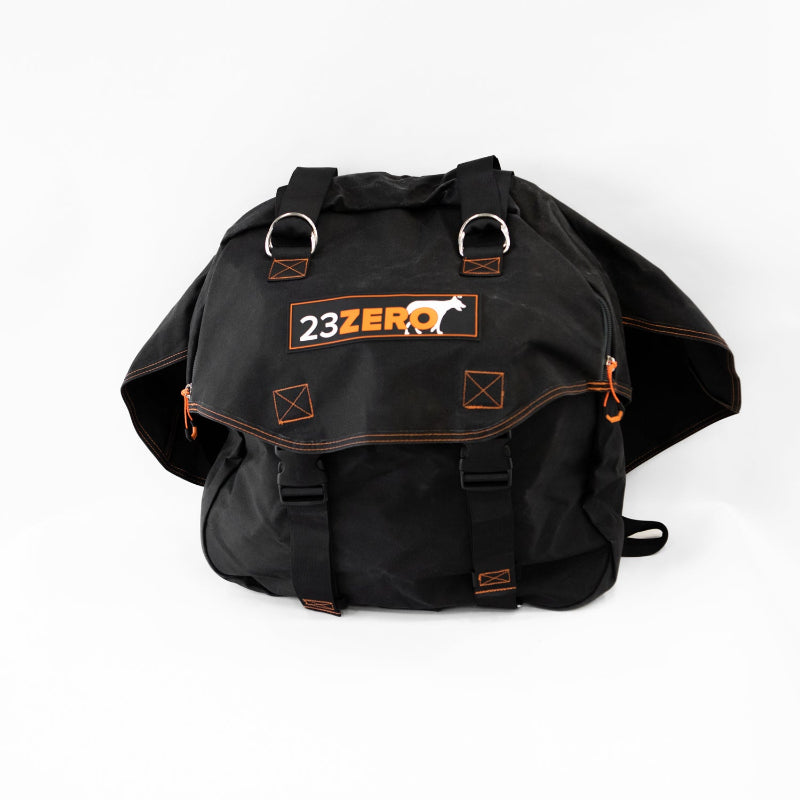 Image of a black 23ZERO spare tire storage bag, shown unmounted and slightly collapsed, with orange stitching, black straps, and metal D-rings, against a white background.
