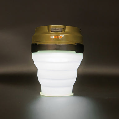 Image of 23ZERO LED solar tent light with collapsible white silicone body and olive green top, front view on dark background.