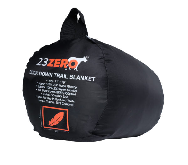 Image of a 23ZERO Duck Down Trail Blanket, compressed in its black stuff sack with product details and a feather logo printed on the side, displayed on a white background.