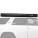 Image of the black 23ZERO Peregrine Pro 270-degree awning in its black transit cover, securely mounted to the roof rack of a white SUV