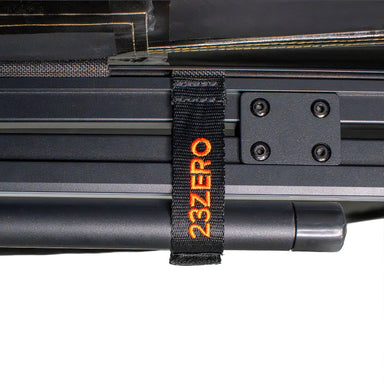 Image of a close-up detail of the Peregrine PRO 180 Awning with the awning arm strapped to the frame for storage. The black webbing strap has the 23ZERO logo embroidered in orange, highlighting the quality and branding of the product's hardware