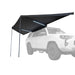 Image of a Peregrine PRO 180 Awning partially deployed with LED lights on, angled front and side view. The black fabric awning is mounted to the side of a white SUV, which is ghosted out in the background