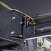Image of a close-up detail of the Peregrine PRO 180 Awning bracket and mounting hinge. The photo shows the heavy-duty black metal bracket and bolts, highlighting the awning's sturdy connection to the vehicle