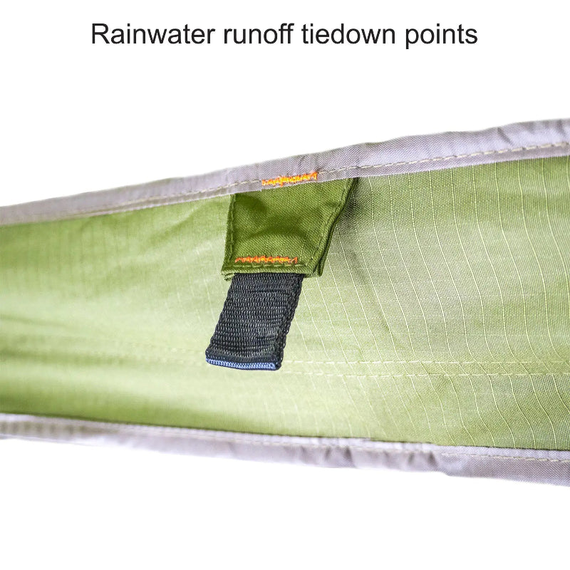 Image of a close-up on the green fabric of a 23ZERO Peregrine Awning, showcasing a reinforced black webbing tiedown loop. The loop is securely stitched with orange thread, providing a point for rainwater runoff