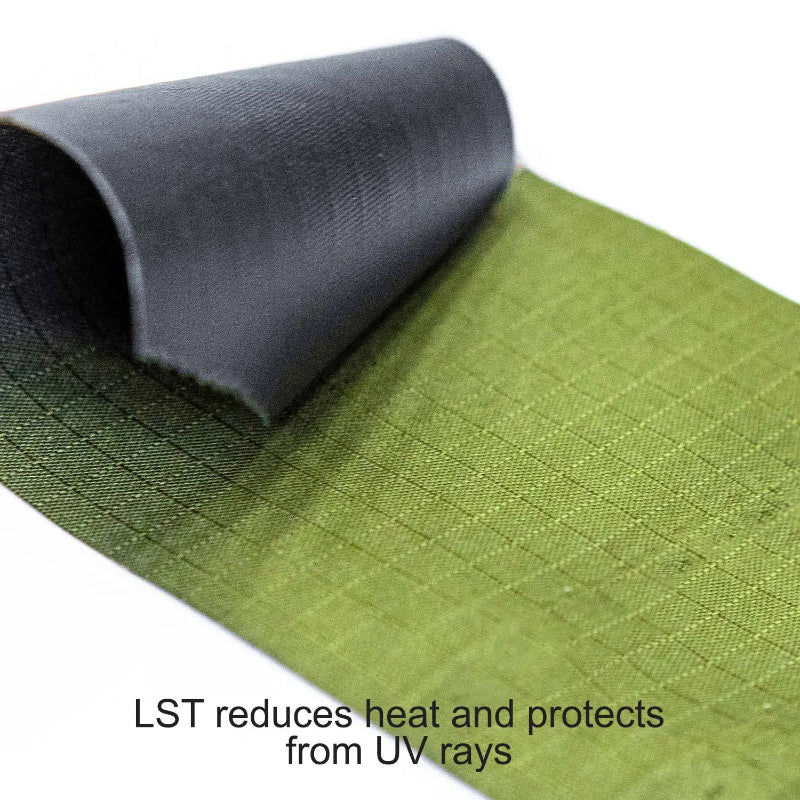 Image of a close-up on the two-layer fabric of a 23ZERO Peregrine Awning, with the green exterior ripstop material shown. The corner is peeled back to reveal the black LST (Light Suppression Technology) coating on the underside, which reduces heat and protects from UV rays