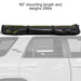 Image of a 23ZERO Peregrine 180 Compact Awning partially rolled up and secured with black straps on a vehicle's roof rack. The green fabric with a black underside is visible, showing the awning in its compact, travel-ready state