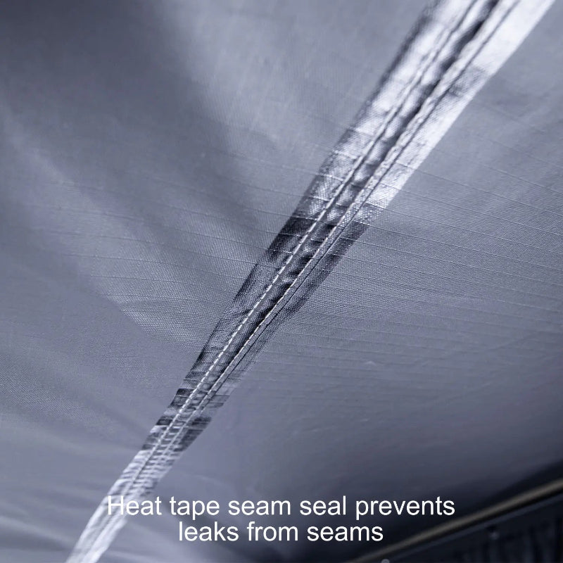 Image of a close-up, high-angle view of the underside of a 23ZERO Peregrine 180 Compact Awning. The black waterproof fabric shows a prominent seam sealed with a strip of heat tape to prevent leaks