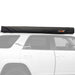 Image of 23Zero Peregrine Pro 270° 5-arm awning in its closed transit cover, black fabric with 23Zero logo, mounted on the roof of a white vehicle, side view with vehicle silhouette