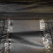 Close-up image of a dark green fabric with a black zipper, yellow stitching, and shiny reinforced seams, possibly from an awning or tent