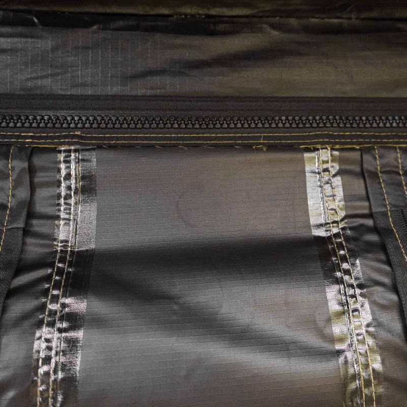 Close-up image of a dark green fabric with a black zipper, yellow stitching, and shiny reinforced seams, possibly from an awning or tent