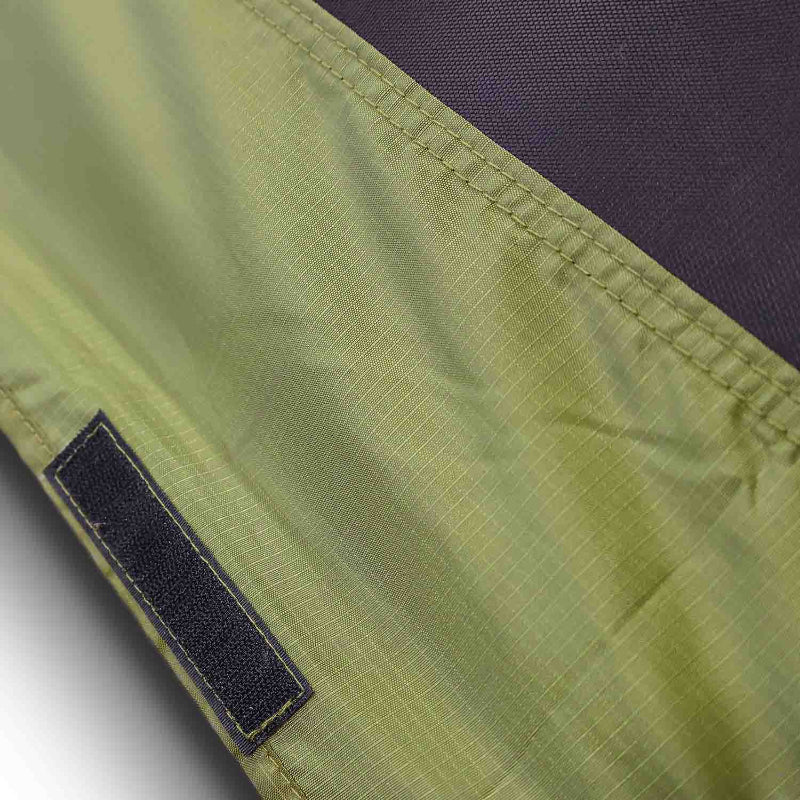 Close-up image of olive green ripstop fabric with visible stitching and a black hook-and-loop fastener, possibly from a tent or awning