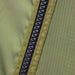 Close-up image of a black heavy-duty zipper on olive green ripstop fabric, showing the texture and stitching in detail