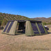 Image of a large, green 23ZERO Peregrine wall kit fully deployed and attached to an awning, enclosing a white Jeep Rubicon in a spacious outdoor room. The wall kit features multiple mesh screen windows and is set up in a sunny, dry, grassy landscape with distant mountains under a clear blue sky