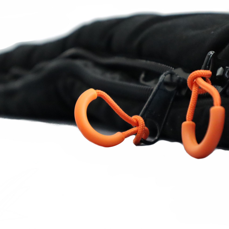 Image of a close-up of two orange zipper pull tabs on a black fabric, with the zipper itself partially visible.