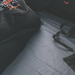 Image of grey fitted mattress sheet installed inside rooftop tent with sleeping bag and straps, close-up angled interior view in low light setting.