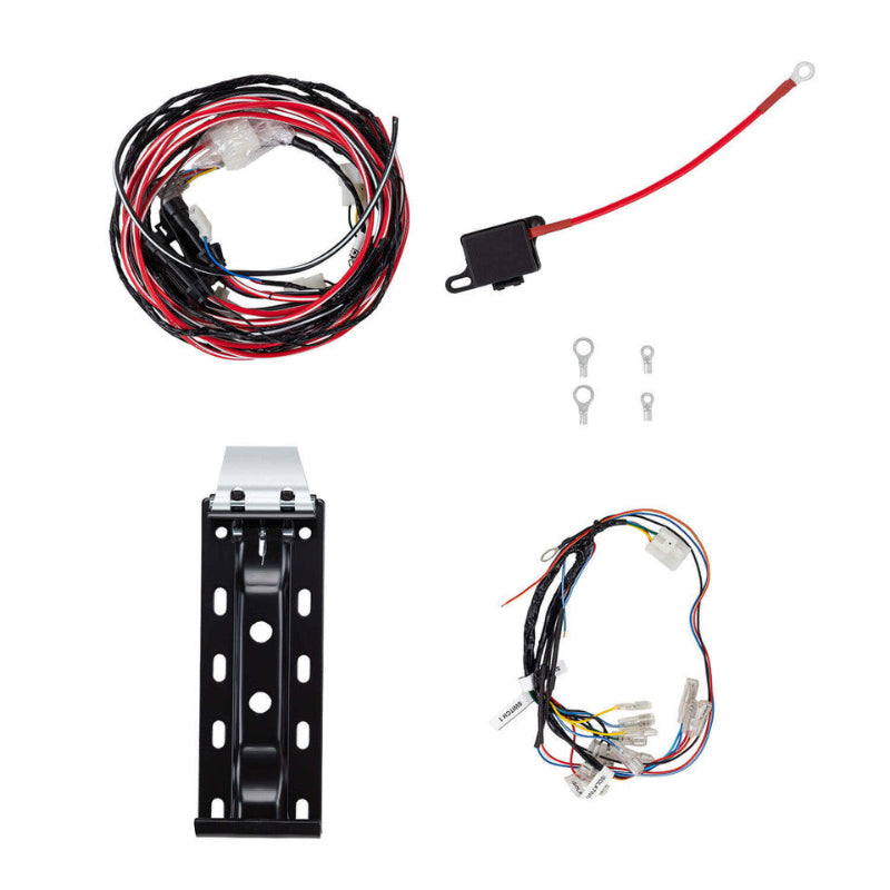 Image showing four components: a coiled red and black wiring harness, a single red power cable with an inline fuse and ring terminal, a black metal mounting bracket, and a multi-colored wiring harness with switch labels, all on a white background