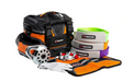 Image of an ARB Premium Recovery Kit on a white background, featuring a black and orange recovery bag, tree trunk protector strap, two bow shackles, a snatch block, and leather gloves. All items are laid out in front of the bag for a clear view