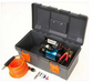 Image of an ARB Portable Air Compressor in an open gray toolbox with orange latches on a white background. The blue and black compressor is in the case with the orange air hose and fittings resting next to it
