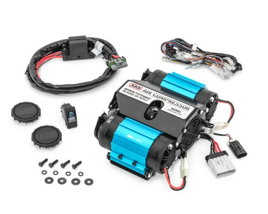Image of an ARB Air Compressor kit, featuring the main compressor unit with blue accents, various wiring harnesses, a switch, and small parts like caps and screws, all presented on a white background. This comprehensive kit provides on-board air supply for various needs