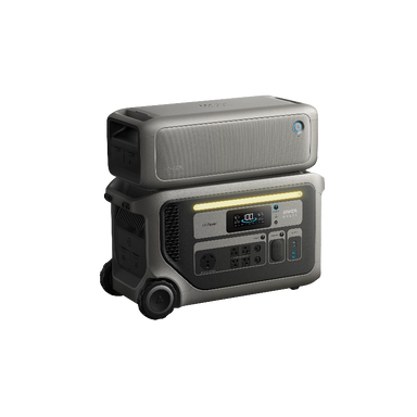 Image of Anker SOLIX F3000 portable power station with stacked expansion battery on top, illuminated LED light bar and front power ports visible, rugged gray wheeled design, angled front and side view on transparent background.
