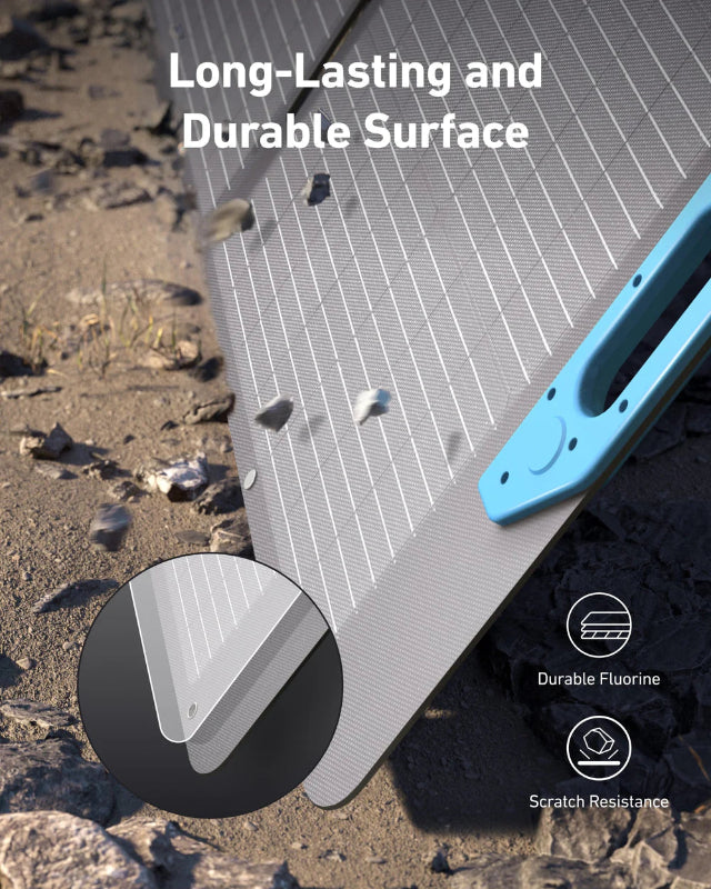 Image of Anker SOLIX portable solar panel demonstrating durable, scratch-resistant surface with protective fluorine coating, black photovoltaic panel with blue handle, close-up angled view on outdoor ground background.