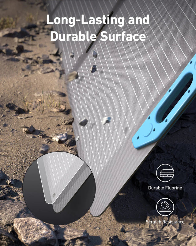 Image of Anker SOLIX portable solar panel highlighting long-lasting, scratch-resistant surface with fluorine coating, black photovoltaic panel with blue handle, close-up angled view on rocky outdoor background.