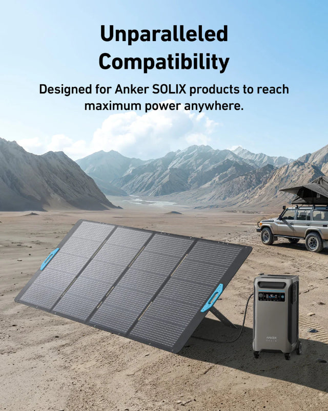 Image of Anker SOLIX portable solar panel connected to a power station in a desert landscape, foldable black panel with blue handles and angled stand, wide front and side view in outdoor camping setting.
