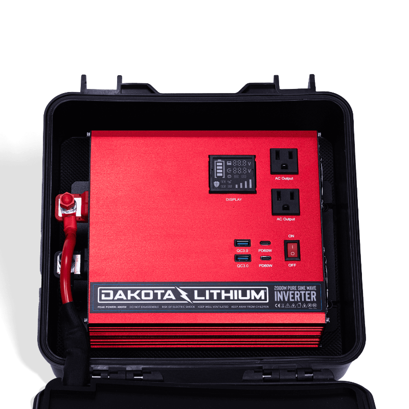 Image of an open Dakota Lithium Powerbox 135 revealing a red 2000W Pure Sine Wave Inverter with display, AC outputs, and USB ports, front view on a dark background