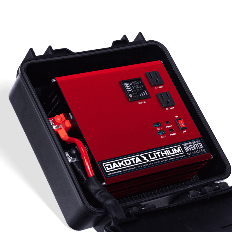 Image of an open Dakota Lithium Powerbox 135 revealing a red 2000W Pure Sine Wave Inverter with display, AC outputs, and USB ports, angled top-down view on a dark background