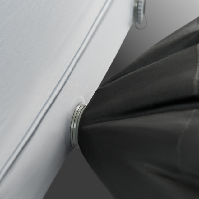Image of the Dometic High-Rise sleeping pad's valve with a silver ring, connected to a black air pump bag, on a gray background.