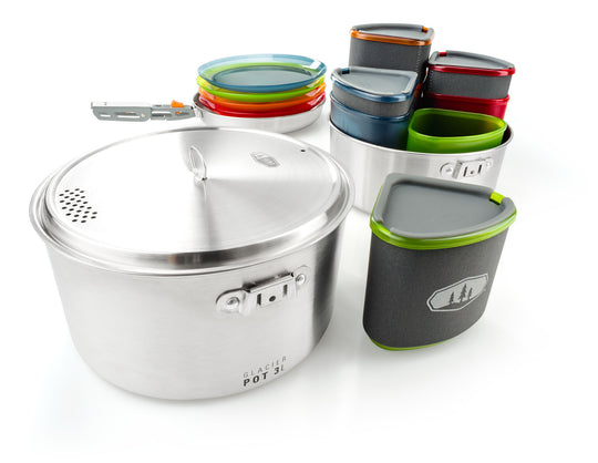 Image of the GSI Outdoors Glacier Pot 3L cookset components laid out, featuring the large pot with lid, various colorful plates, and nested insulated mugs, on a white background.