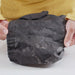 Image of hands holding worn tent fabric with visible wear and abrasion marks, close-up front view showing damaged material before sealing.