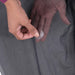 Image of a hand placing a clear round repair patch onto gray tent fabric, close-up view showing patch application process.