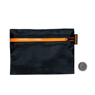 Image of compact black zippered gear pouch with orange waterproof zipper and logo tag, flat front view with a coin for size reference on a white background.