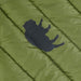 Image of a black animal-shaped adhesive repair patch applied to green quilted outdoor fabric, close-up angled view showing patch adhesion and texture.