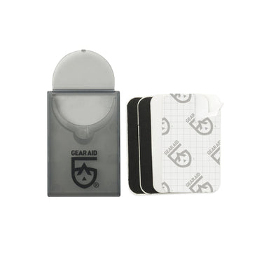 Image of Gear Aid Tenacious Tape mini repair patches with compact pocket case and stacked pre-cut black and clear patches, front-facing product view on white background.