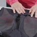 Image of hands smoothing and testing a jacket zipper after lubrication, black fabric garment laid flat, close-up front view on neutral background.