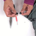 Image of hands holding replacement zipper slider components with pliers and needle tool on a work surface, close-up front view on white background.