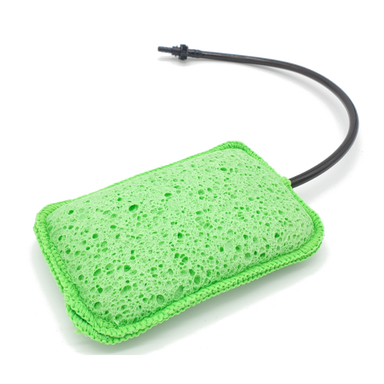 Image of Geyser Systems green scrub sponge attachment with porous texture and black hose connection, angled front view on white background.